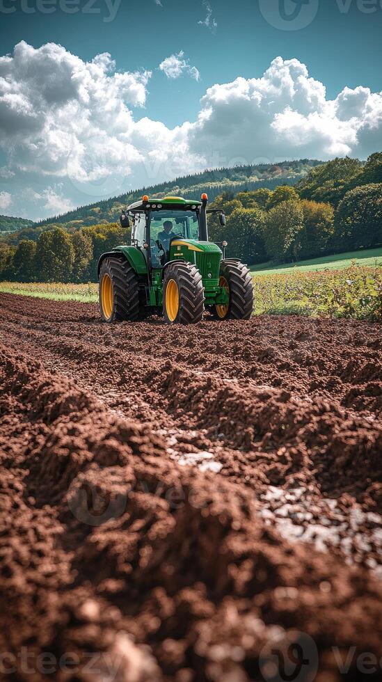 Farmer driving modern tractor plowing red dirt field for sowing photo