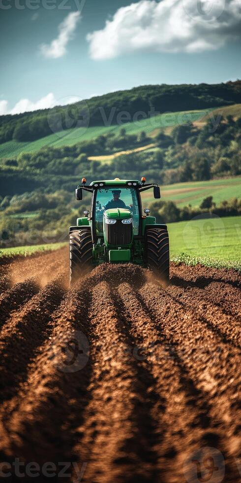 Farmer driving modern tractor plowing red dirt field for sowing photo