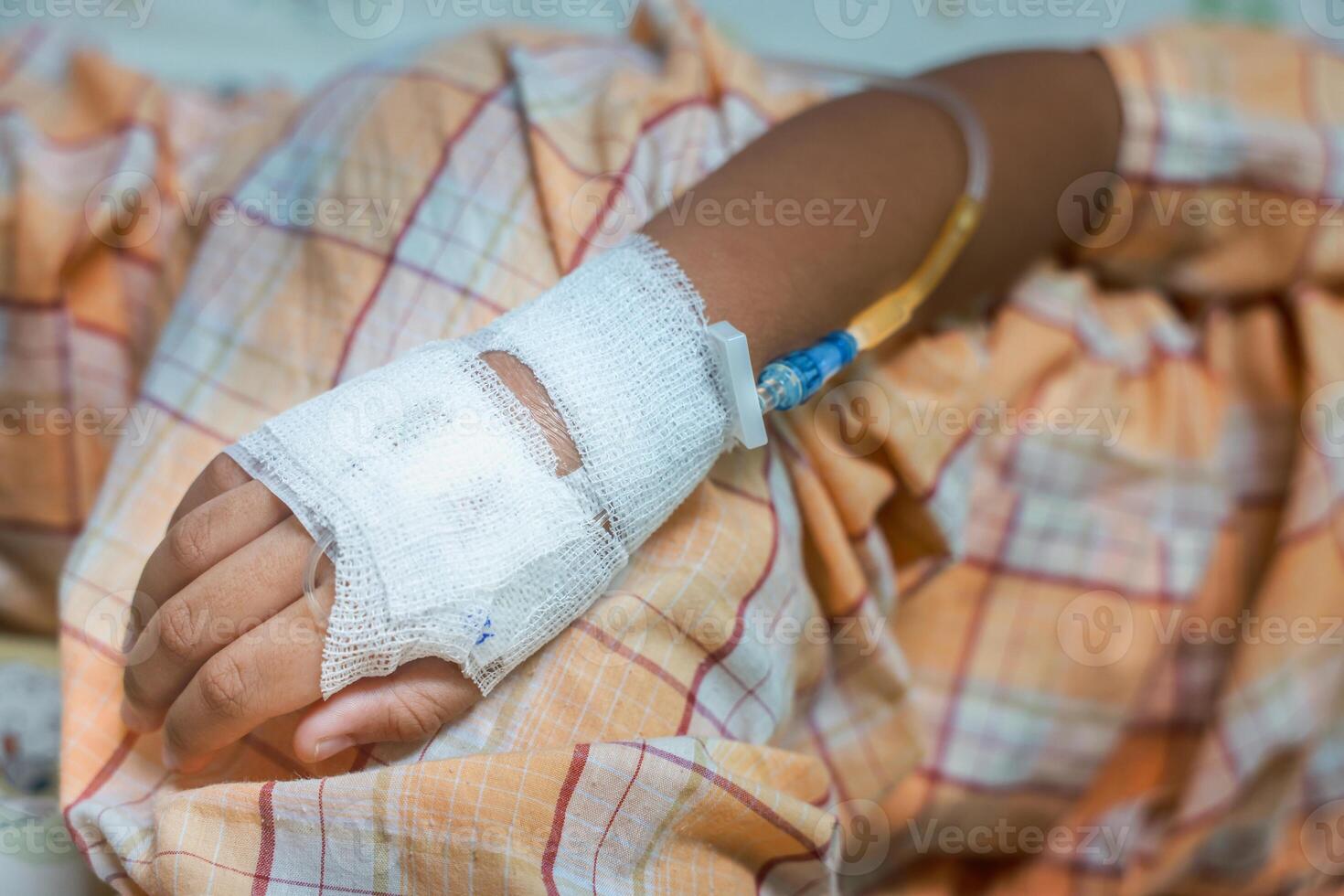 Close up child hand with tube of normal saline infusion at the hospital because it is influenza A. Hand of a patient in Hospital ward. Concept about treatment, emergency, medical, chemotherapy, sick. photo