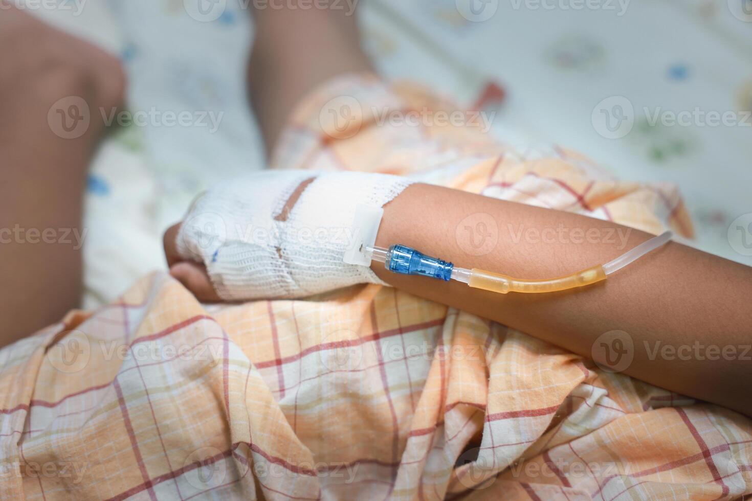 Close up child hand with tube of normal saline infusion at the hospital because it is influenza A. Hand of a patient in Hospital ward. Concept about treatment, emergency, medical, chemotherapy, sick. photo