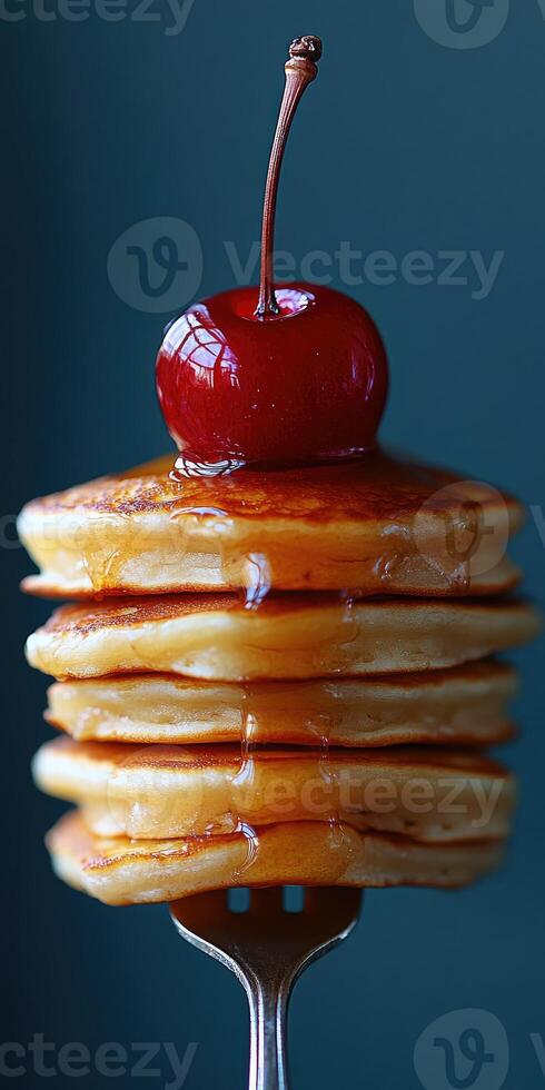 Drizzling maple syrup on stack of pancakes with cherry on top photo