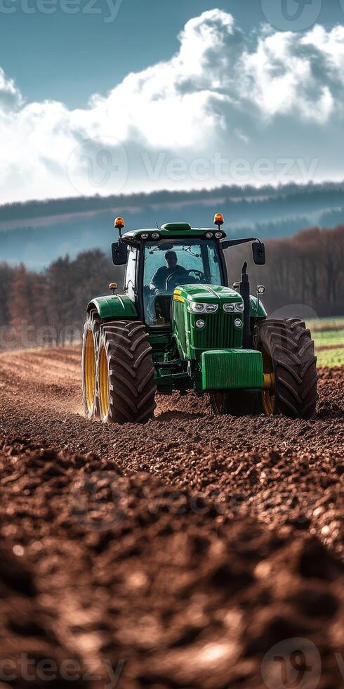 Farmer driving modern tractor plowing red dirt field for sowing photo