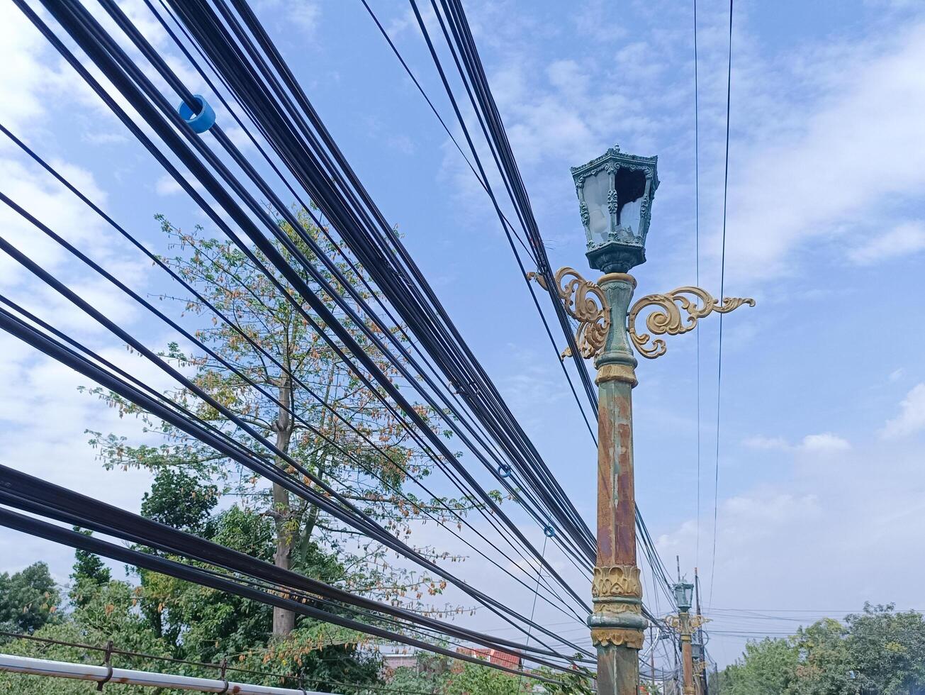 lighting lamp for street with wires running between it and blue sky background photo