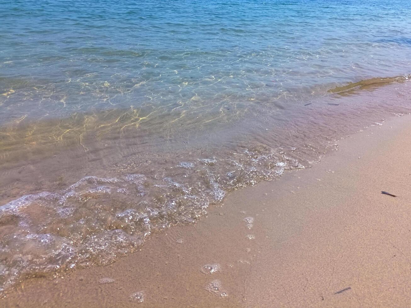 Soft blue ocean wave on fine sandy beach background photo