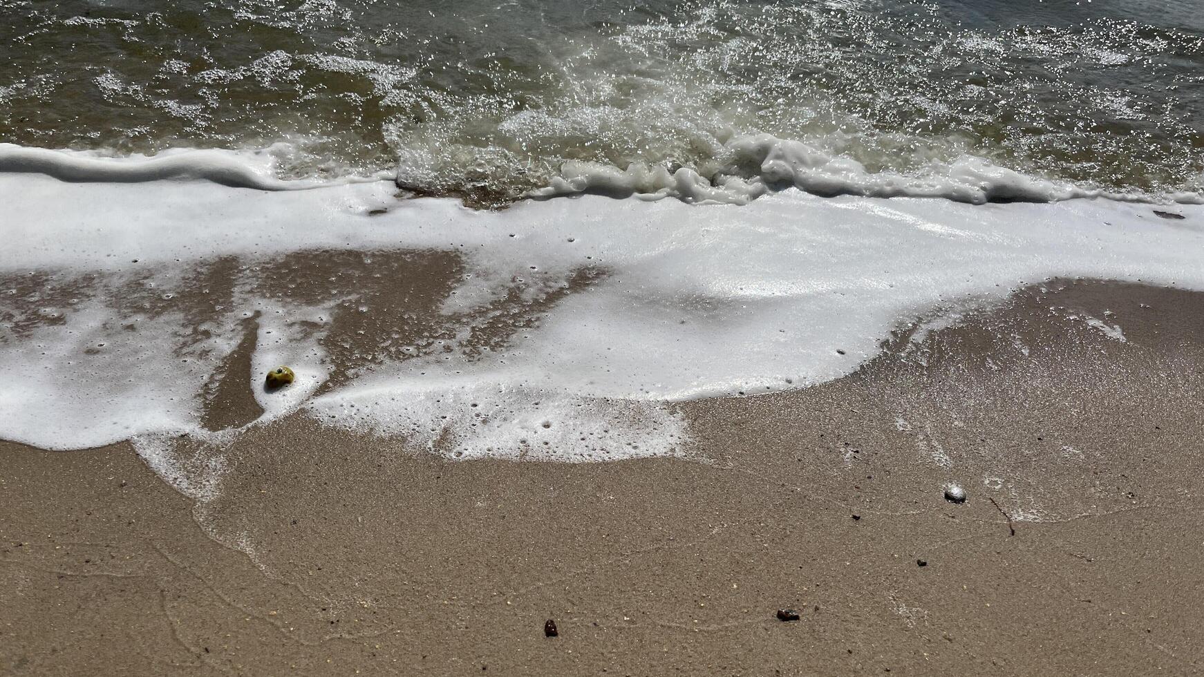 Nature photo of foamy beach waves. Soft wave on sand beach, text copy space for banners, cards. Close up of sea blue waves break on sand