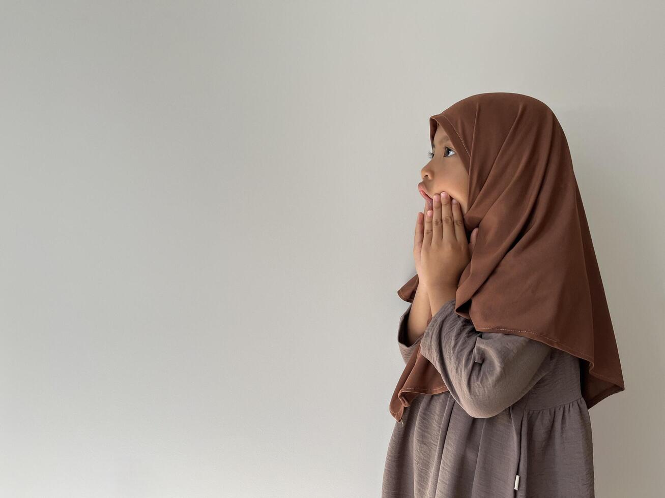 Asian Muslim little girl wearing hijab show shocked gesture. Surprised gesture with copy space photo