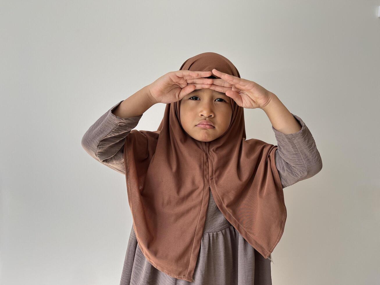 Asian Muslim little girl wearing hijab with both hand in forehead show sad expression. photo