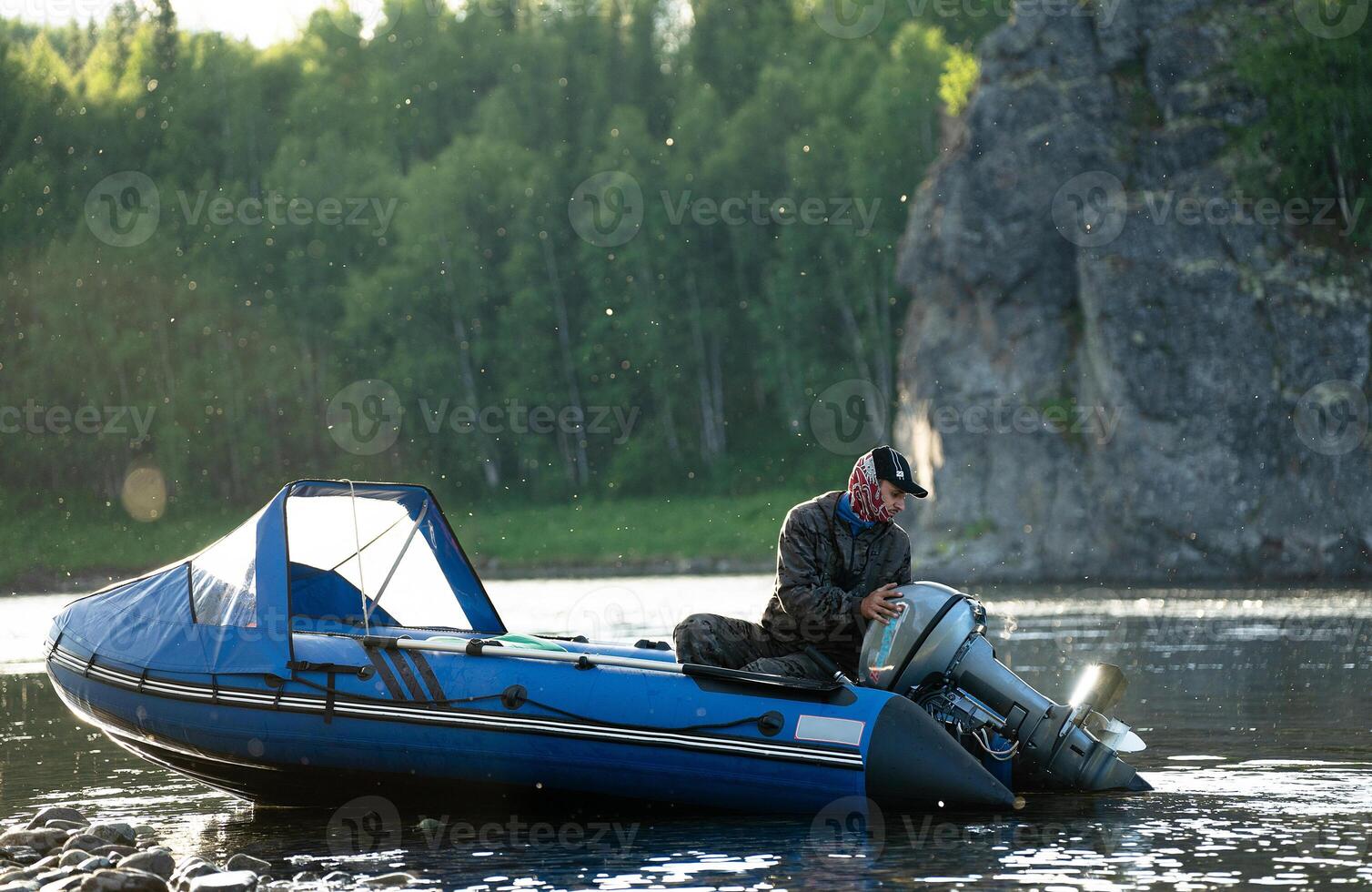 Fisherman on boat keeps motor running at sunset photo