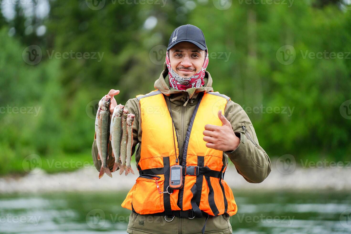 Fisherman showing thumb up with fish in hand photo