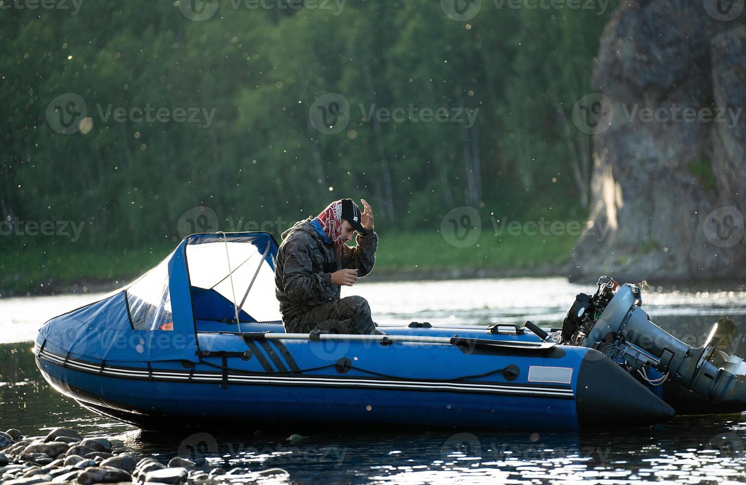 Fisherman on a boat with small mosquitoes on the river in the background photo