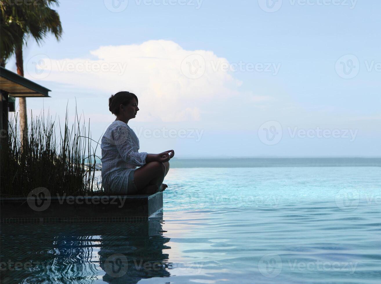 Silhouette of attractive woman sitting in meditating position photo