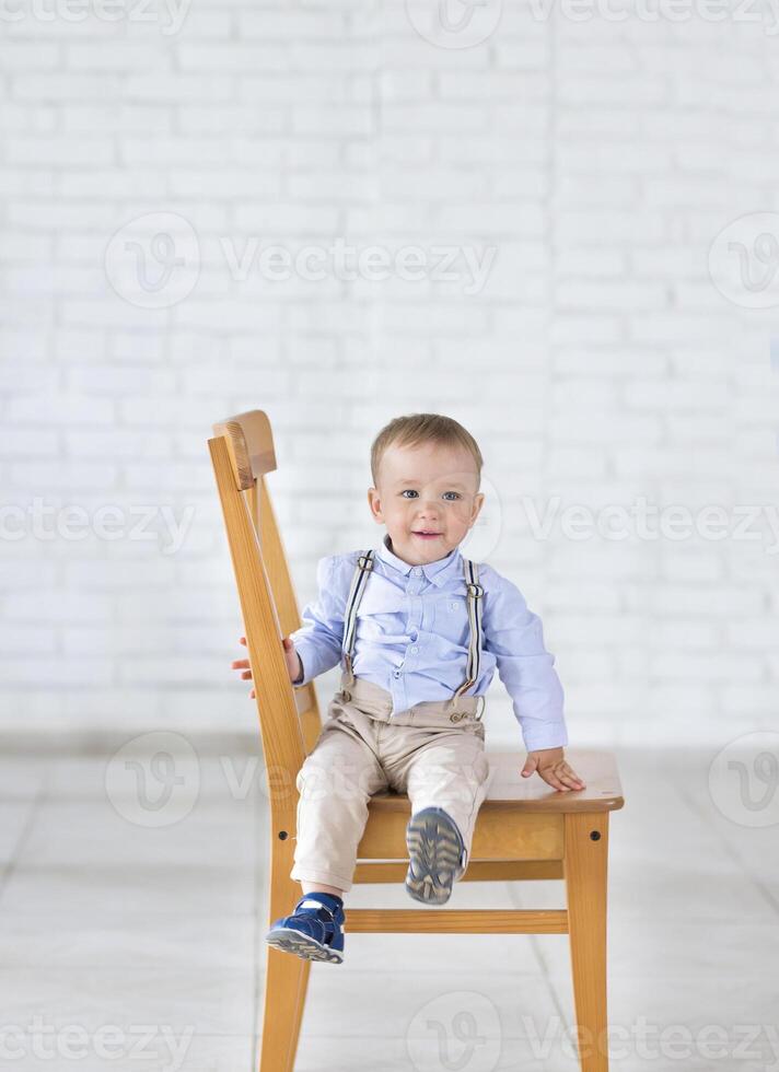 Beautiful adorable laughing baby boy sitting on the chair. photo