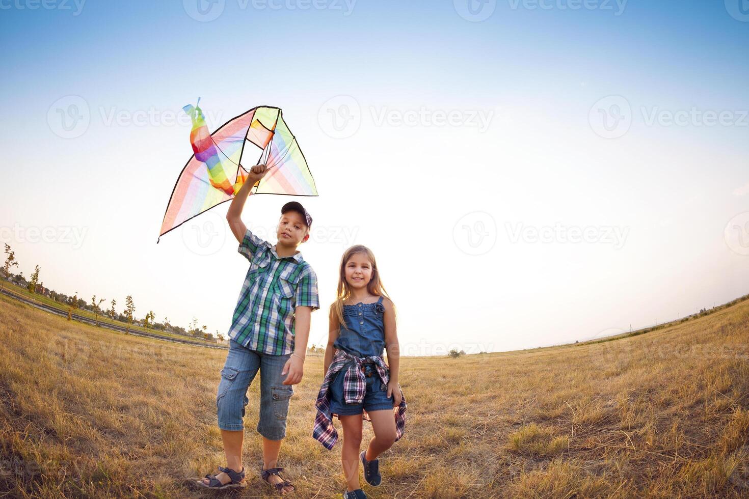 Happy children playing with flying kite on the summer field photo