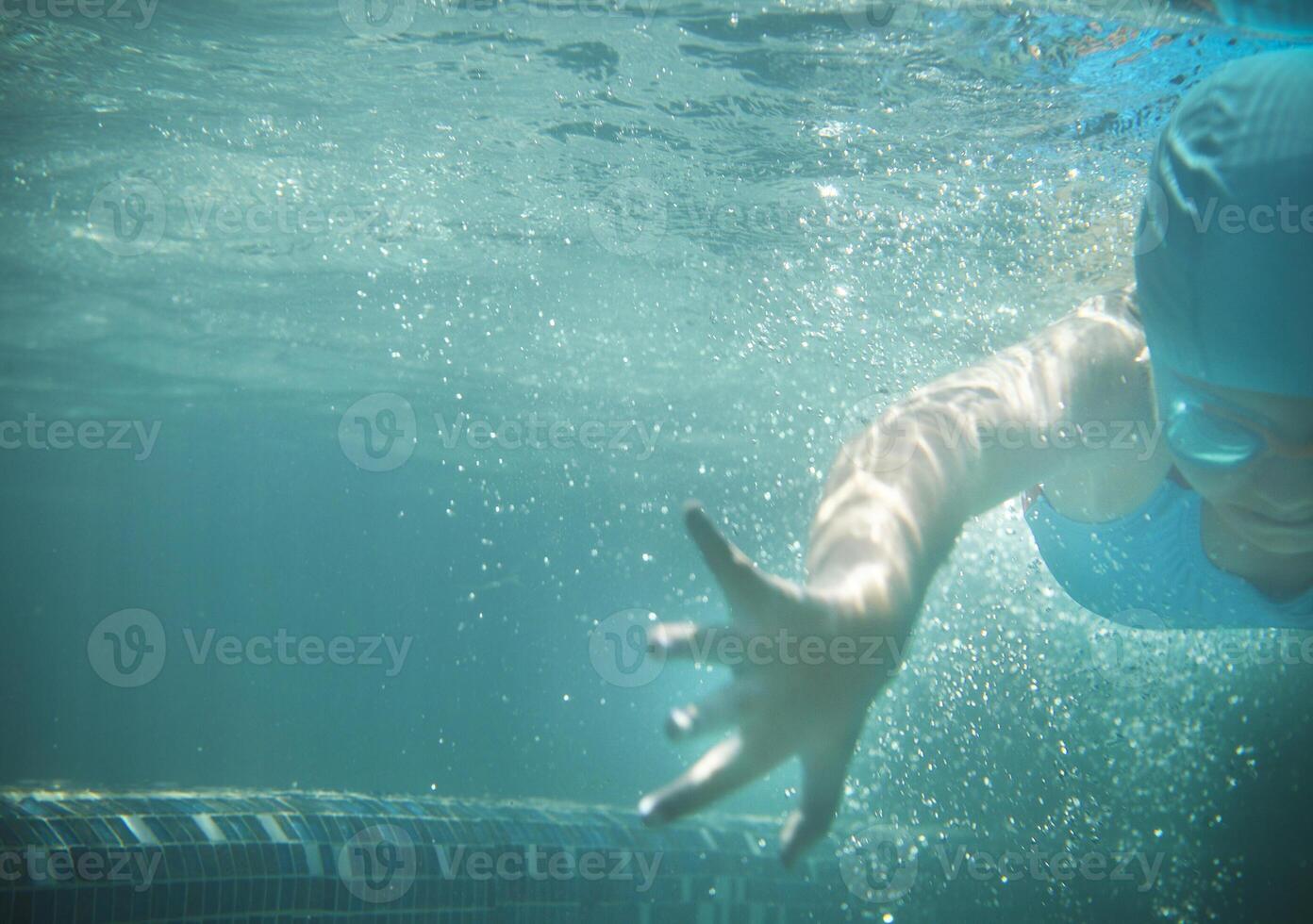 Little girl swims in the pool underwater photo