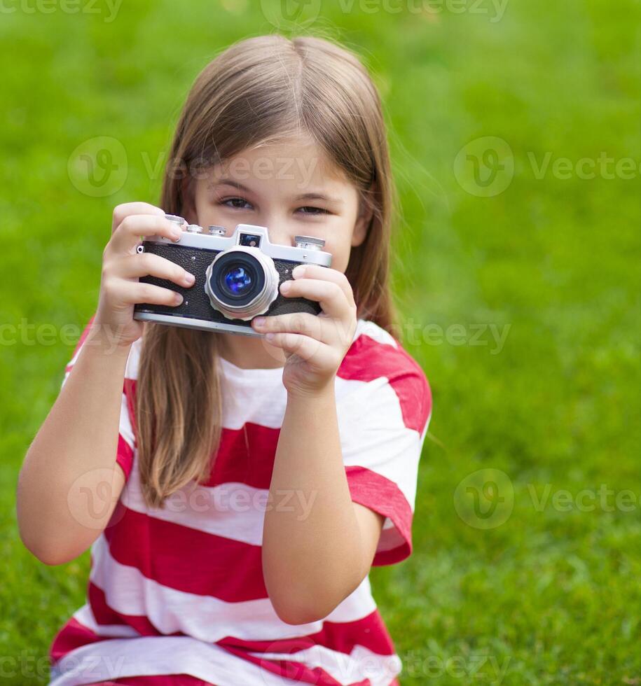 Portrait of a pretty little girl smiling and holding retro camera photo