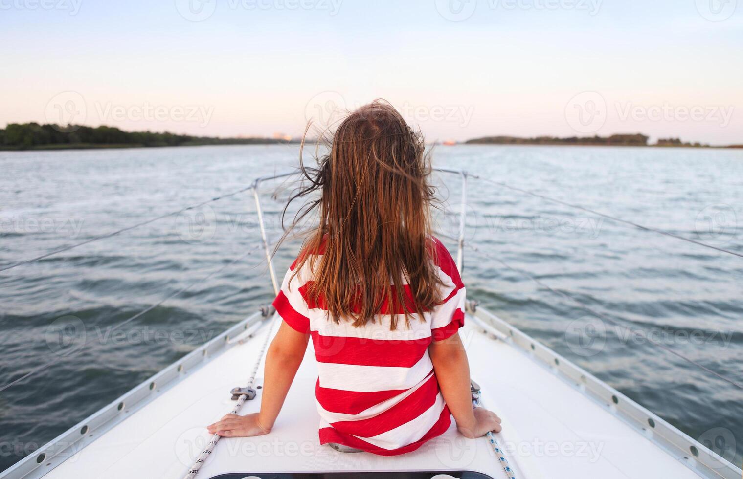 Little girl enjoying ride on yacht at sunset photo