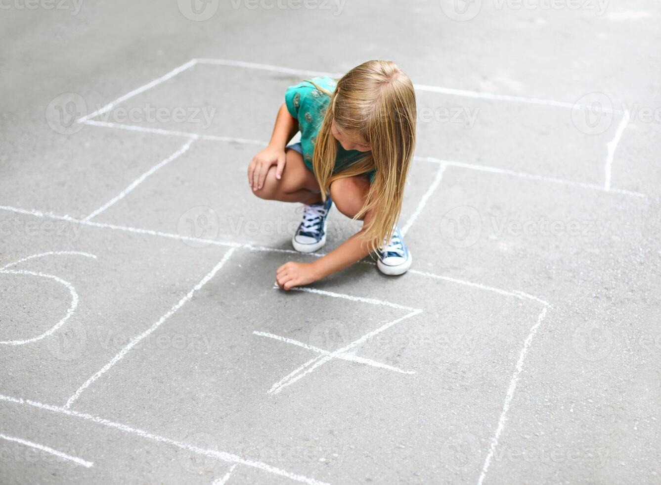 Kid playing hopscotch on playground outdoors photo