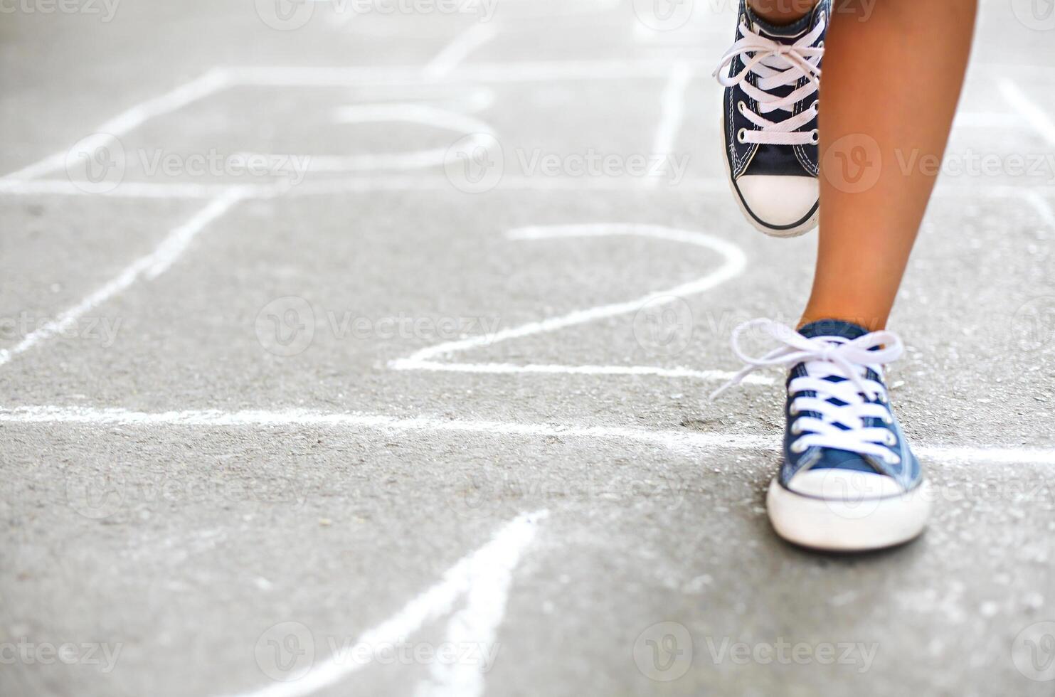 Kid playing hopscotch on playground outdoors photo