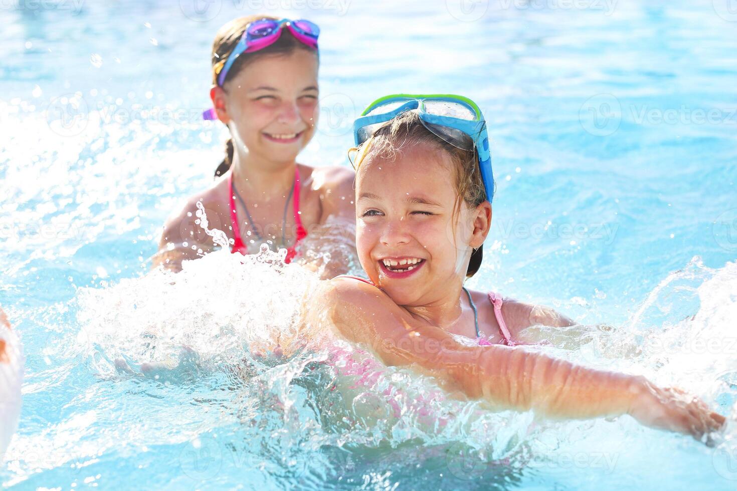 Two cute girls playing in swimming pool photo