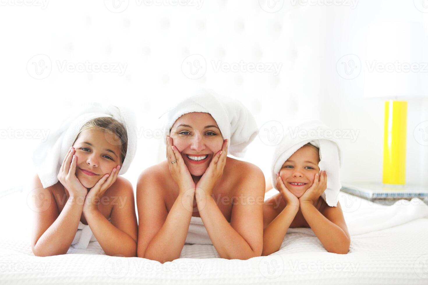 Mother and girls in bathrobes in room after shower photo