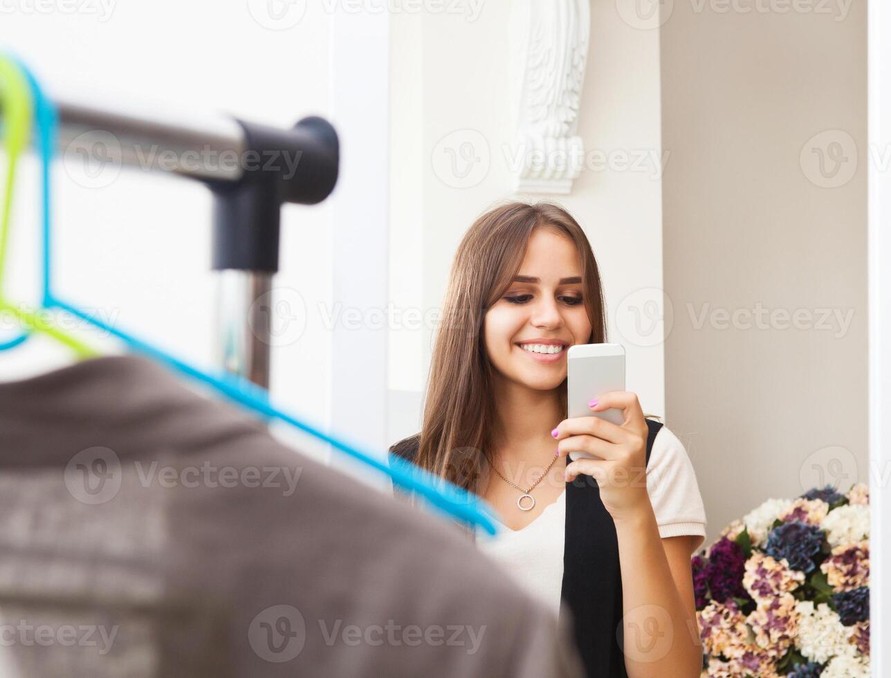 Young girl making photo with mobile camera in shop