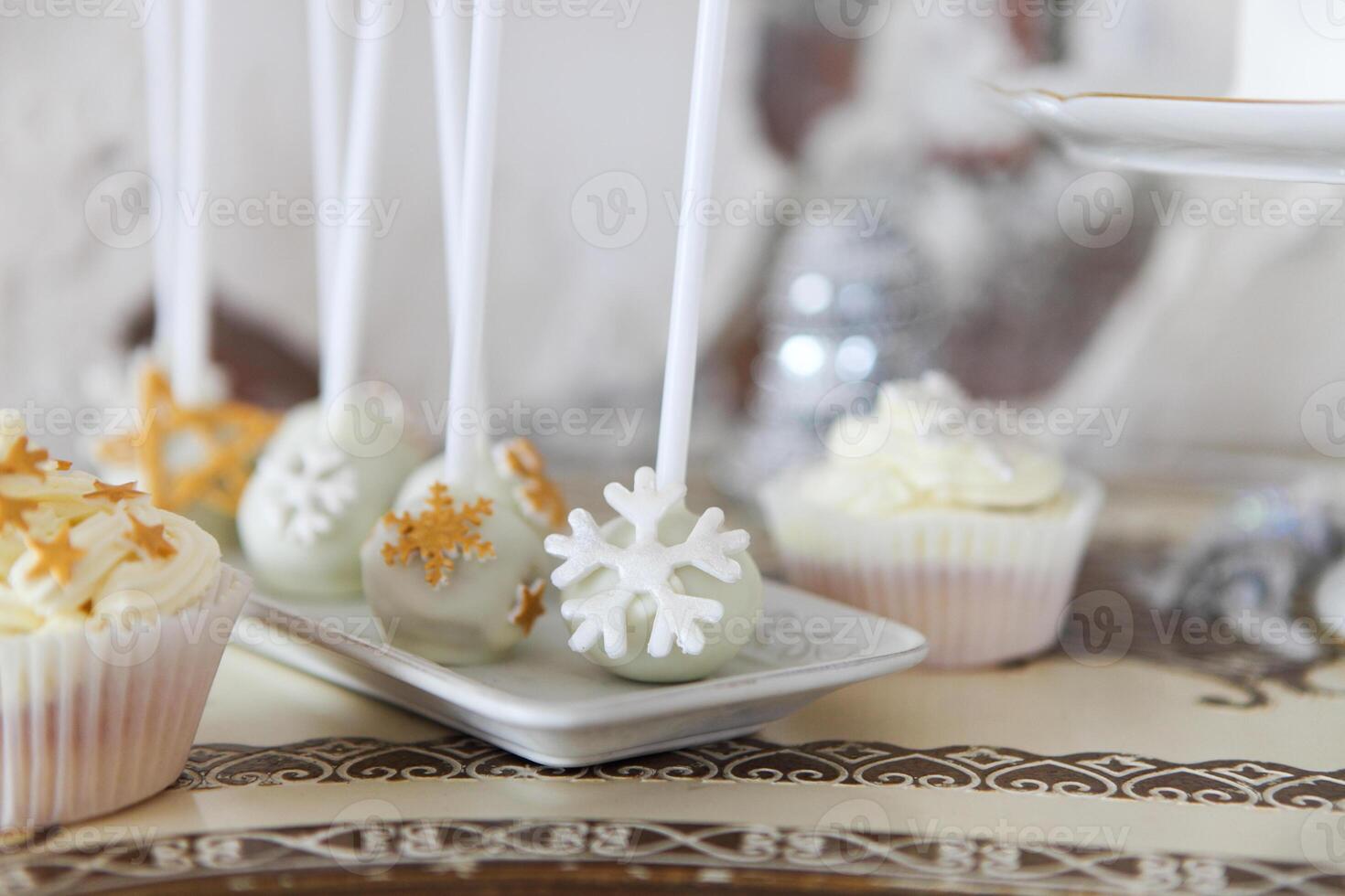 White chocolate Christmas cake pops with snowflakes and cupcakes photo