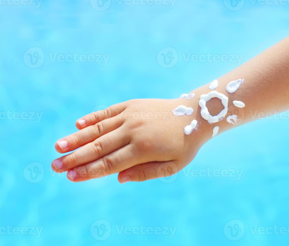 Little hand of the baby with suntan lotion near the pool photo