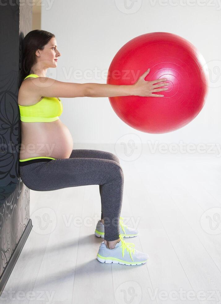 One young pregnant woman doing fitness exercises photo