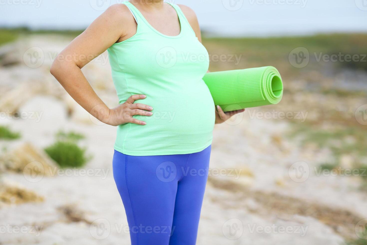 Young beautiful pregnant woman doing exercises on the beach photo