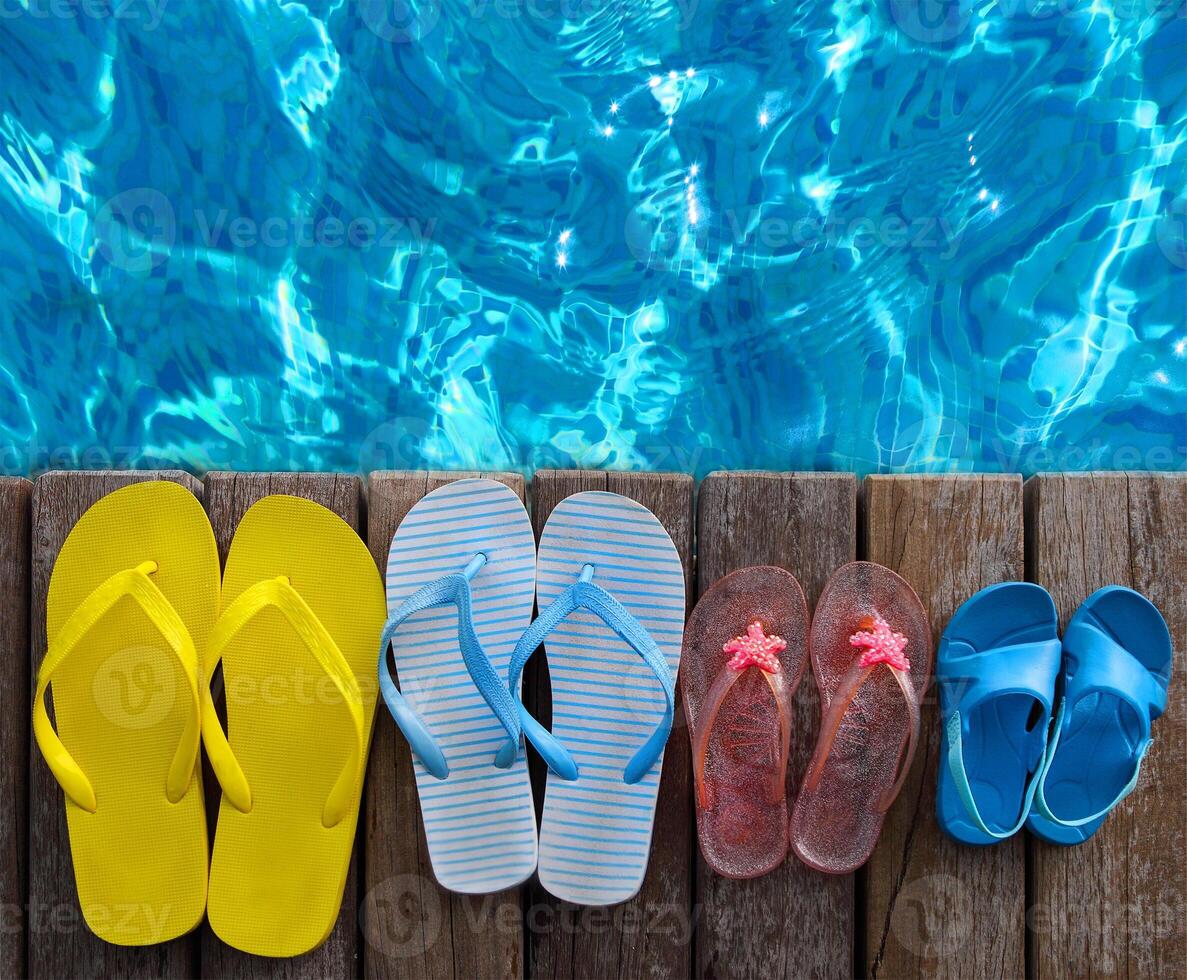 Brightly colored flip-flops on wooden background near the pool photo