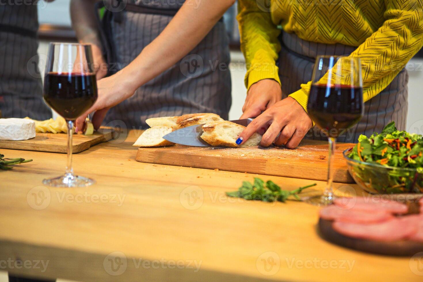 Cheerful female friends preparing a meal together and drinking red wine photo