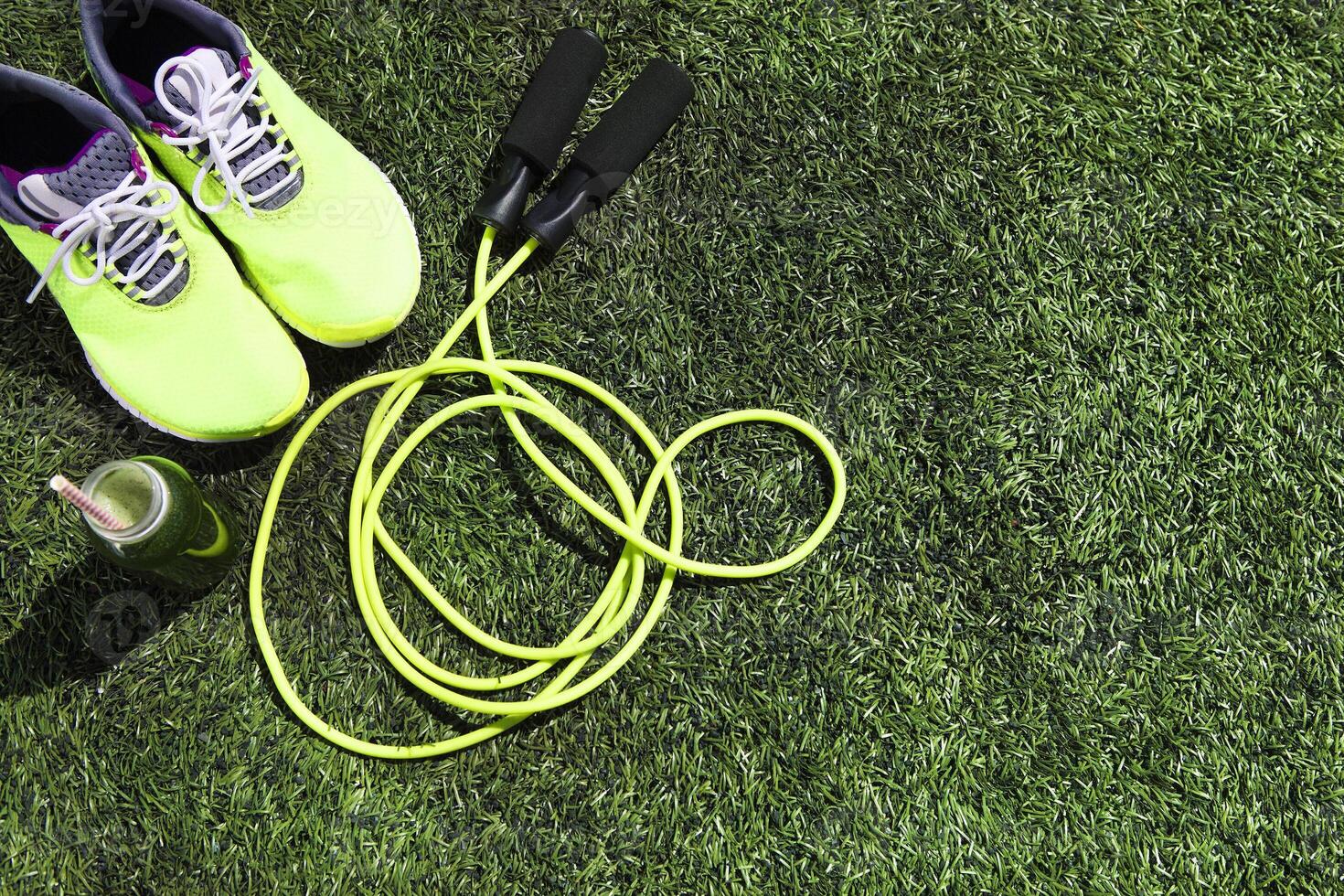Running shoes, jump rope and drink bottle with green juice photo
