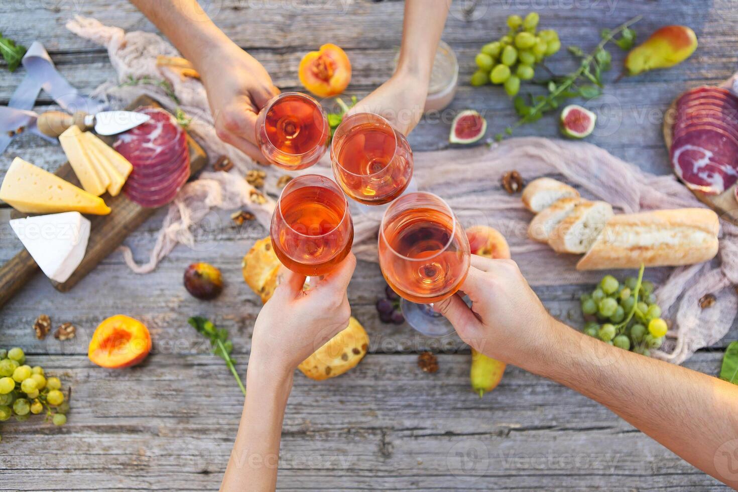 Young people making toast at picnic with rose wine photo