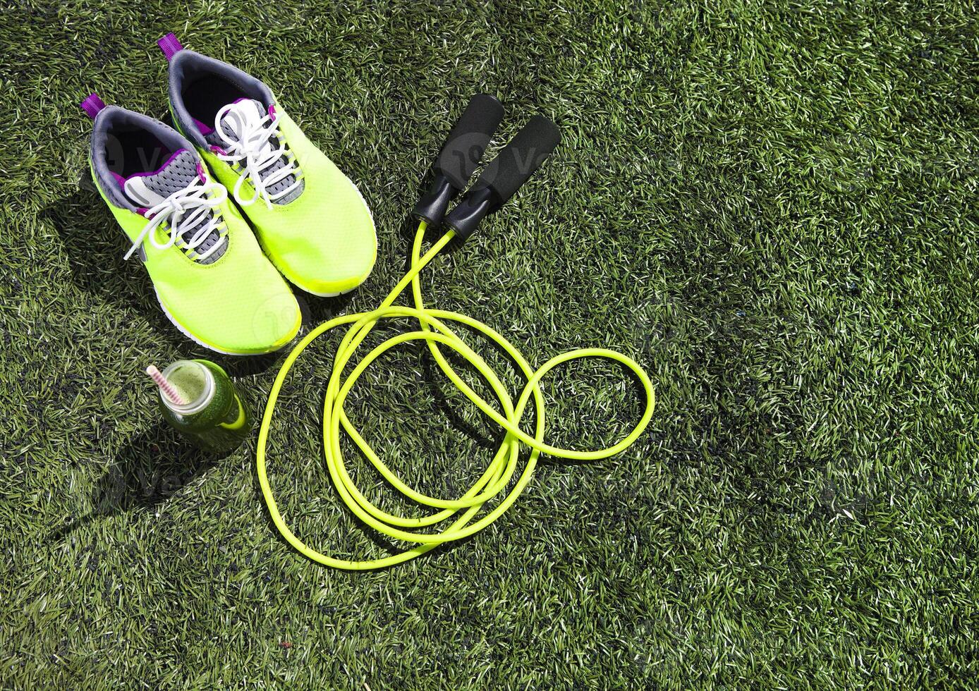 Running shoes, jump rope and drink bottle with green juice photo