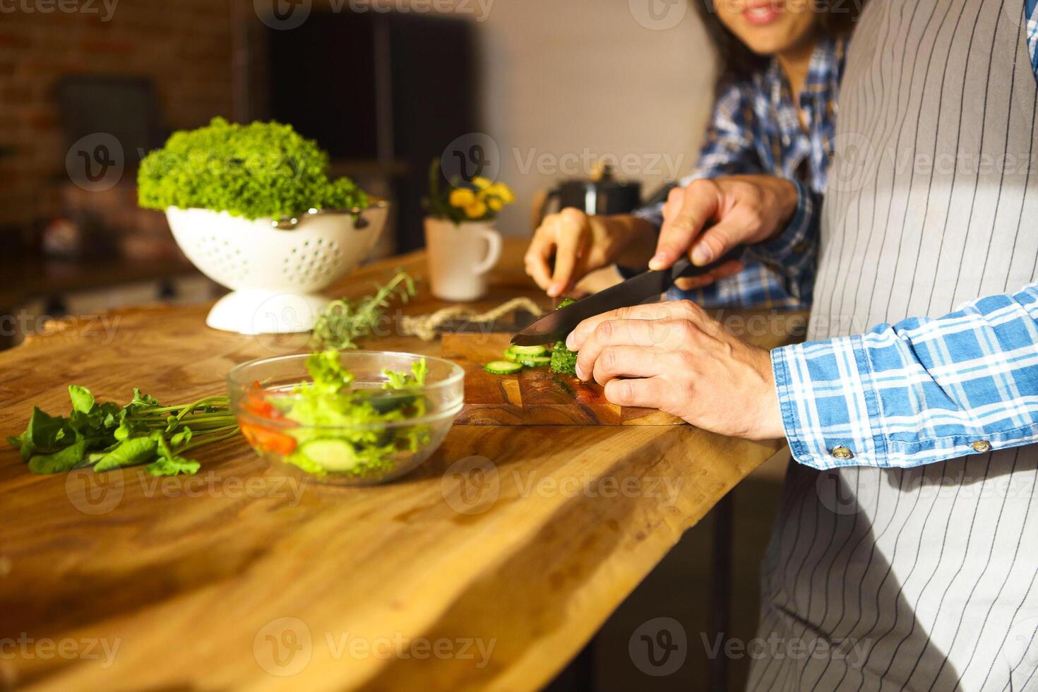 Young man and woman cooking salad together at kitchen photo