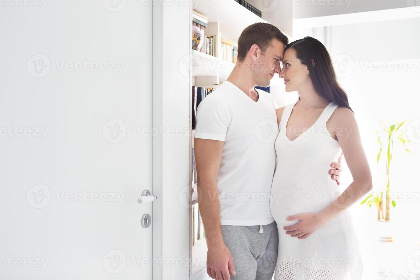 Young man and pretty pregnant woman hugging together photo