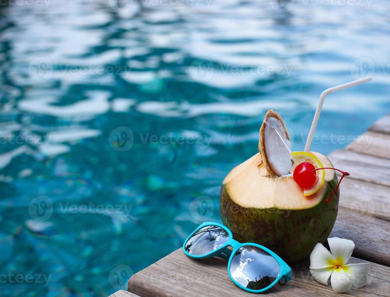 Coconut cocktail with drinking straw by the swimming pool photo
