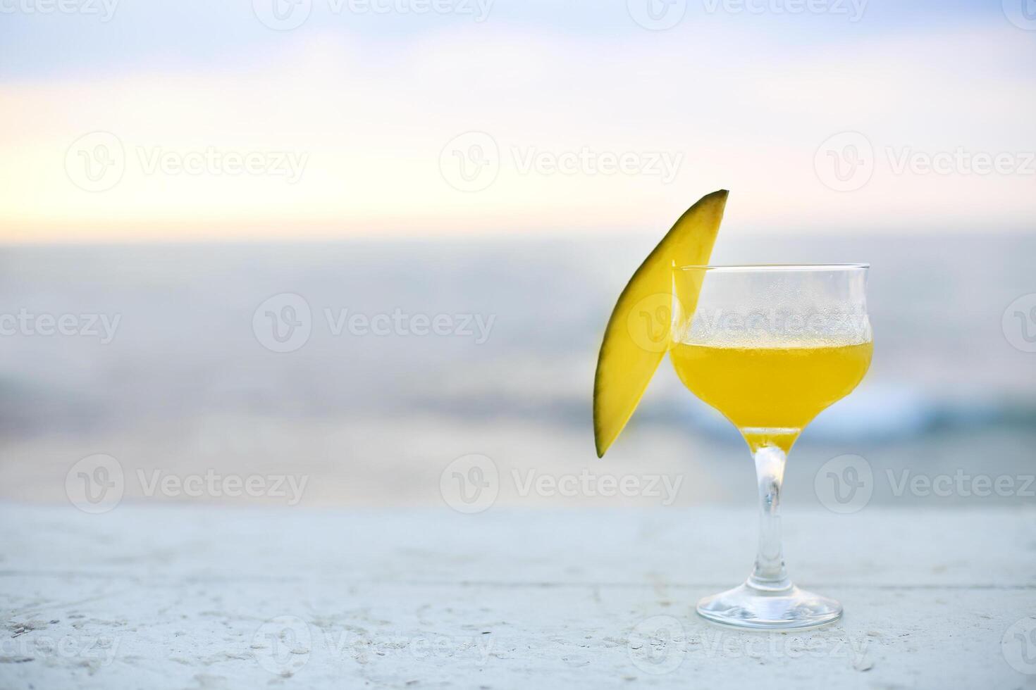 Glass of mango cocktail on bar counter photo