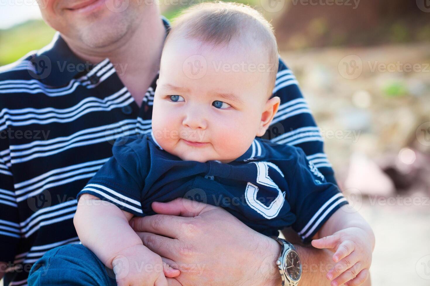 Young father playing with baby son at the beach photo