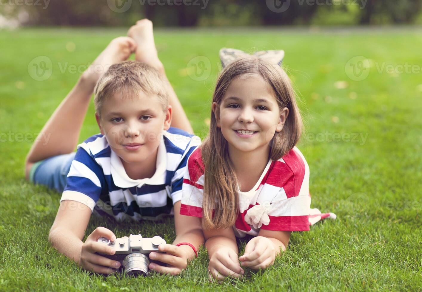 Pretty little brother and sister playing with a camera in summer park photo