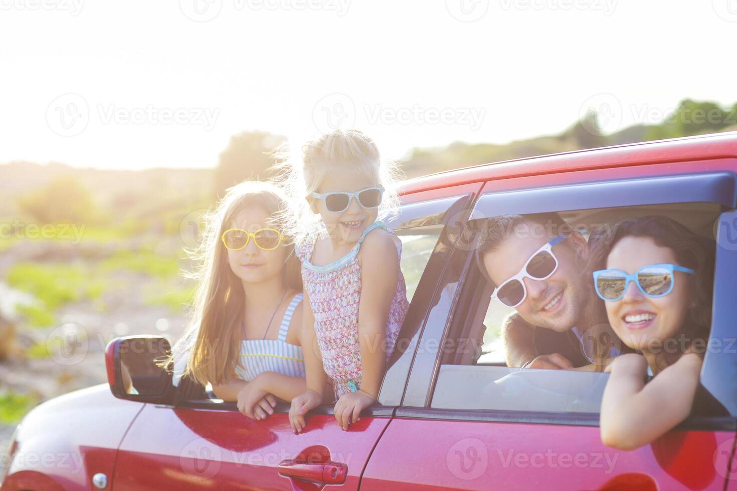 Portrait of a smiling family with two children at beach in the car photo