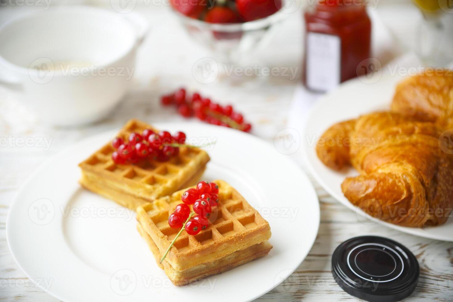 Waffles with red currant jam and berries, croissants, orange juice and oat flakes oatmeal photo