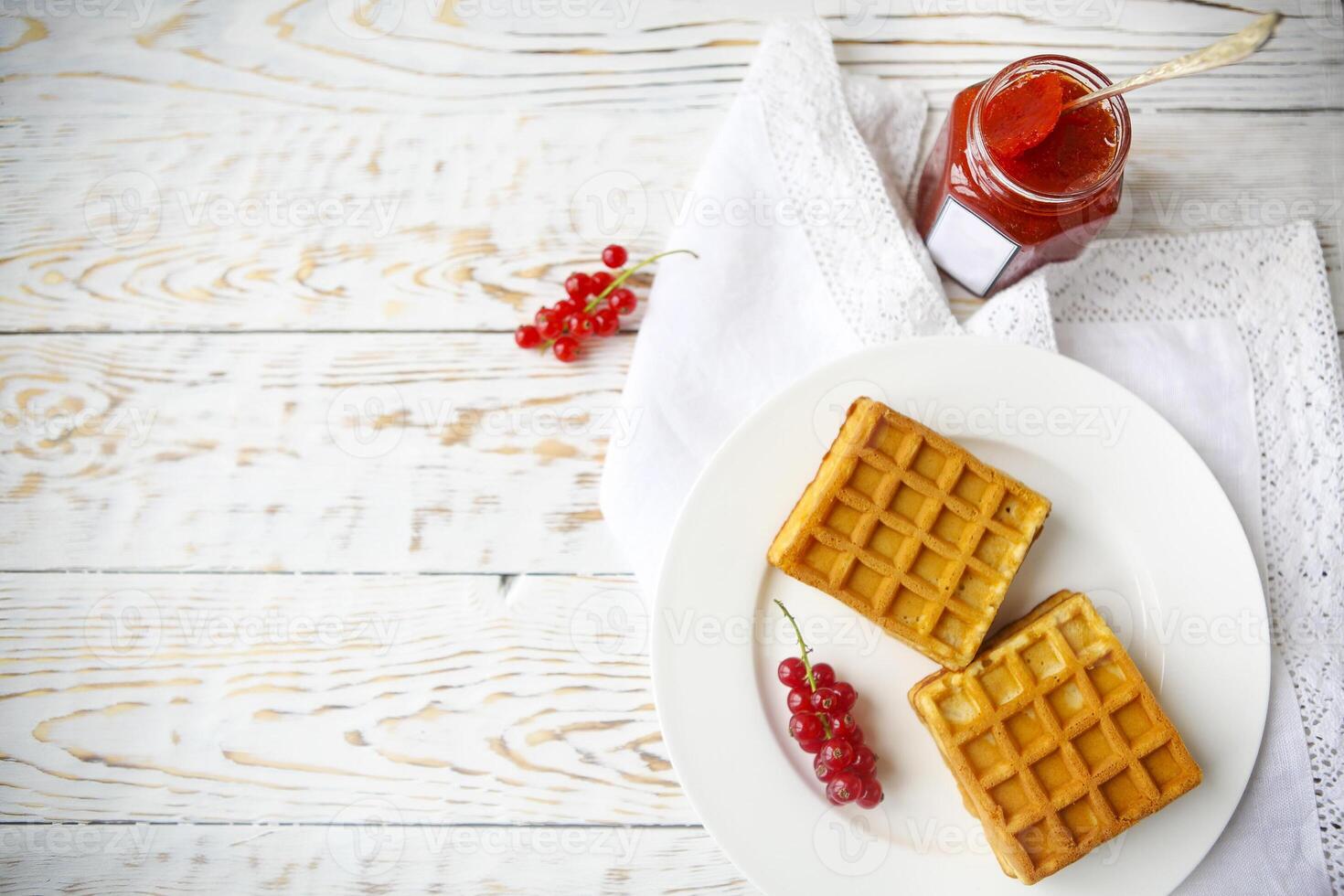 Waffles with red currant jam and berries on a white plate photo