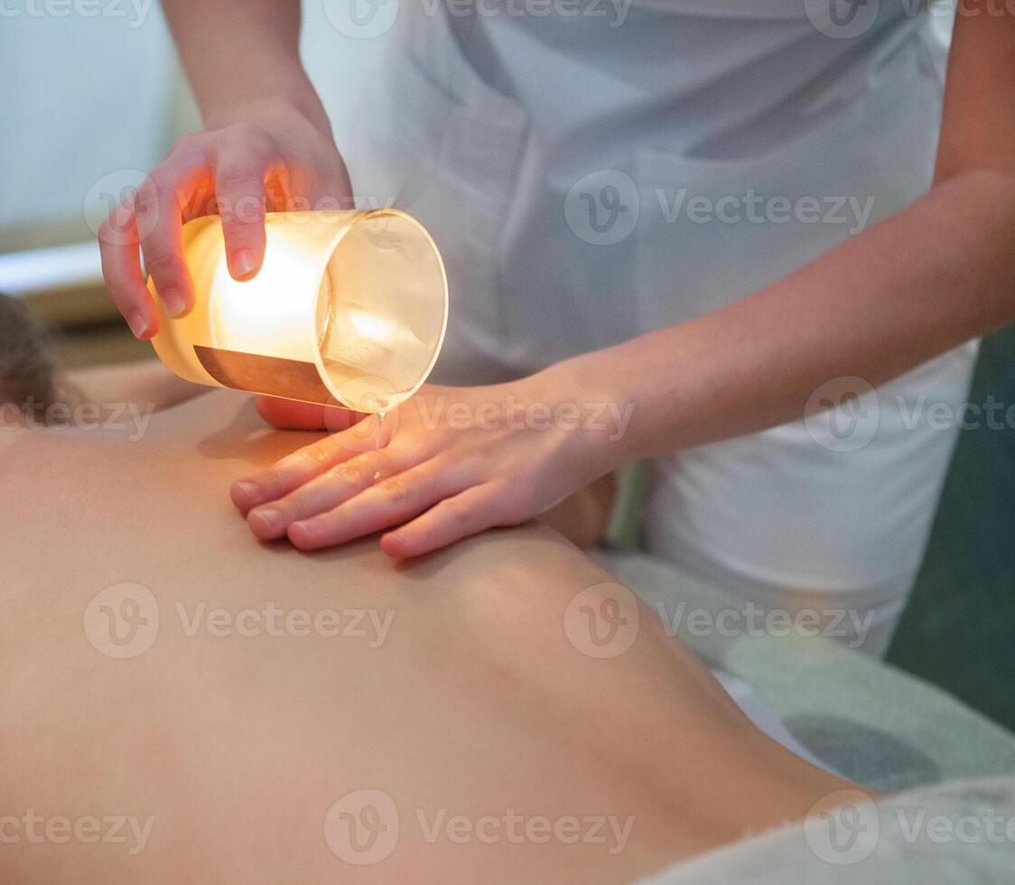 Young woman getting spa massage with massage candle photo