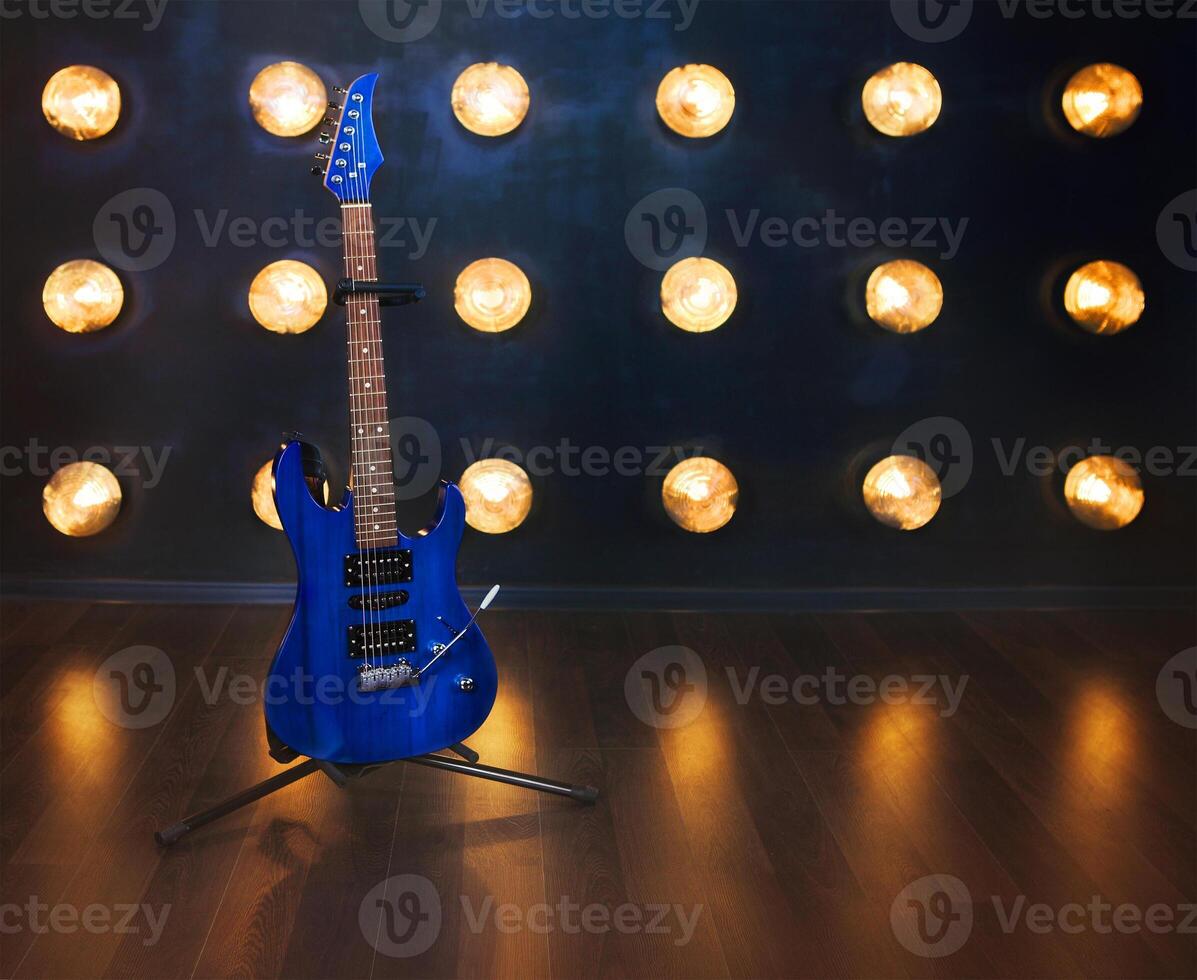 Music concept. Electric guitar standing on the wooden floor near the wall photo