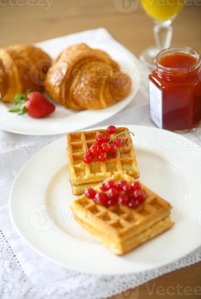 Waffles with red currant jam and berries, croissants, orange juice photo