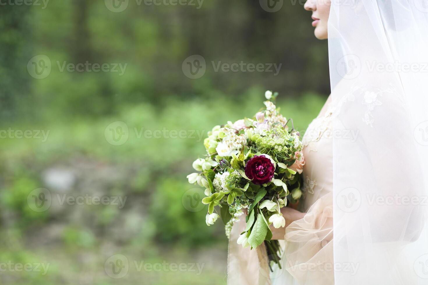 Young bride in wedding dress holding beautiful bouquet photo