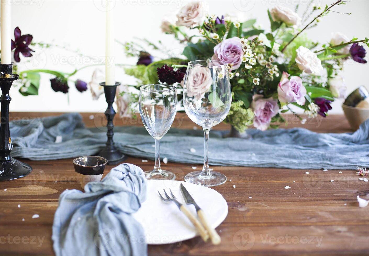 Bouquet of pink flowers on a table set for dinner with candles photo