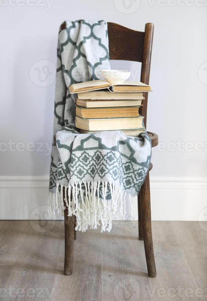 Cup of coffee and books on the wooden chair photo