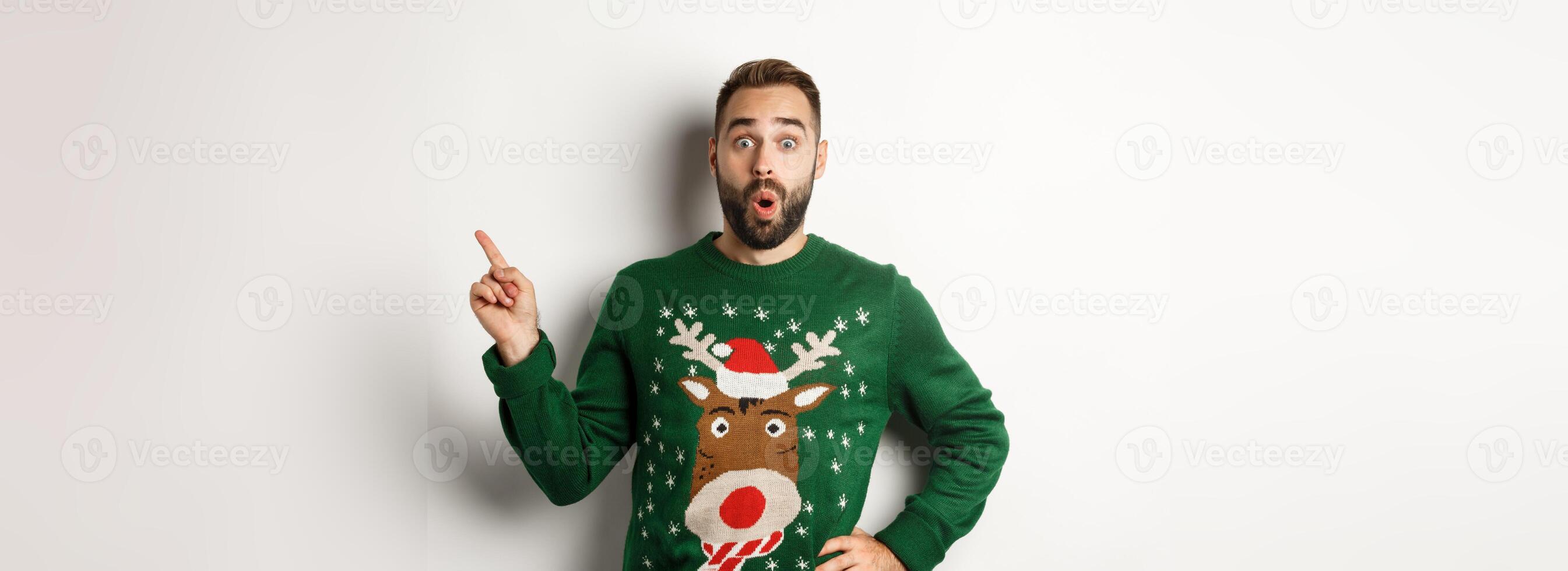 Winter holidays and christmas. Man looking excited as pointing finger right at logo, standing amazed against white background photo